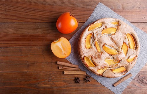 Sweet persimmon pie on brown wooden background. top view, copy space