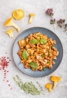 Fried chanterelle mushrooms with basil and spice herbs on gray concrete background. Top view, flat