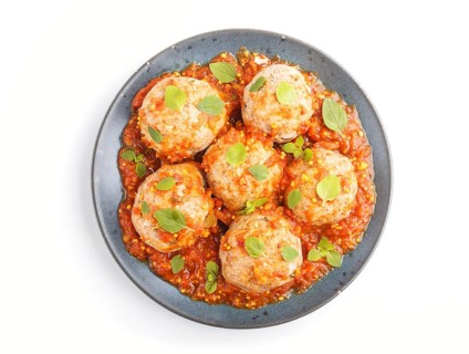 Pork meatballs with tomato sauce, oregano leaves, spices and herbs on blue ceramic plate isolated