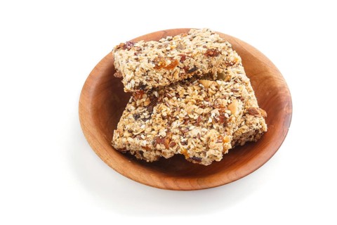 Homemade granola from oat flakes, dates, dried apricots, raisins, nuts in brown wooden plate