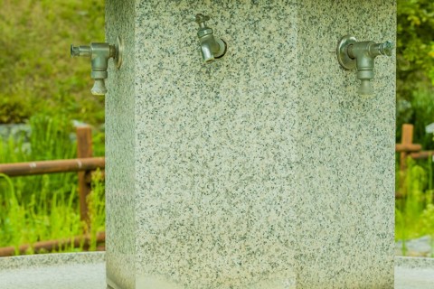 Large hand washing water fountain in a public park with lush green foliage in South Korea