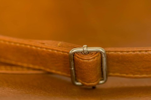 Metal adjustment clip on strap of leather shoulder bag