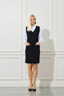 Cute woman in school uniform with hands in pockets next to white wall