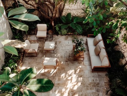 A serene courtyard with tropical plants, stone tiles, and comfortable outdoor furniture bathed in