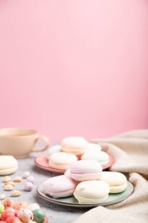 Colored zephyr or marshmallow with cup of coffee and dragees on a gray and pink background and