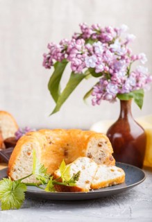Cakes with raisins and chocolate and a cup of coffee. lilac flowers on a gray concrete background,