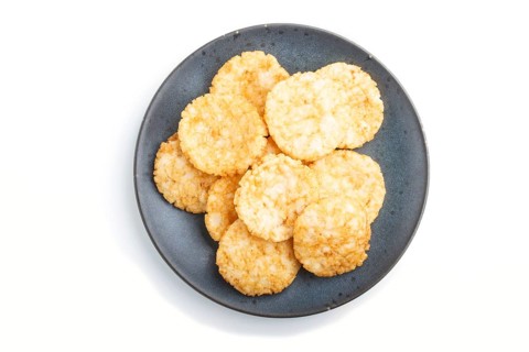 Traditional japanese rice chips cookies with honey and soy sauce on a blue ceramic plate isolated