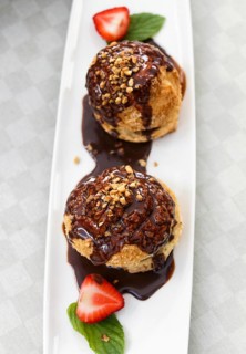 Fresh profiteroles with ice cream and chocolate on a white plate. selective focus. horizontal. top