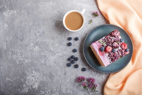 Berry cake with milk cream and blueberry jam on blue ceramic plate with cup of coffee and fresh