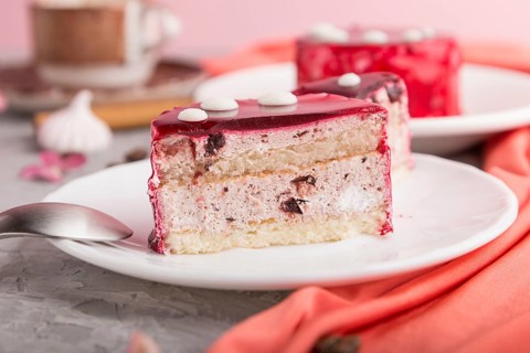 Sliced red cake with souffle cream with cup of coffee on a gray concrete background and red textile