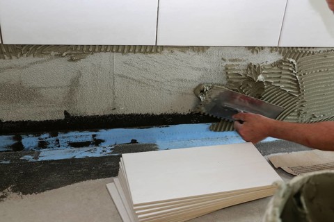 Tiler lays modern wall tiles