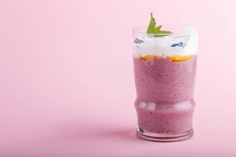 Smoothie with honeysuckle, linen and chia in a glass on pink pastel background. side view, close