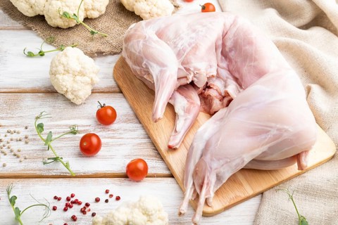 Whole raw rabbit with cauliflower, tomatoes and spices on a white wooden background and linen