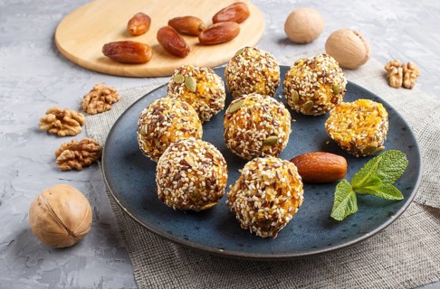 Energy ball cakes with dried apricots, sesame, linen, walnuts and dates with green mint leaves on a