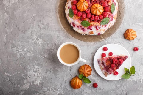 Homemade jelly cake with milk, cookies and raspberry on a gray concrete background with cup of