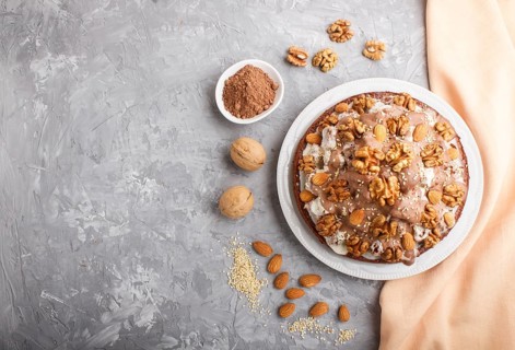 Homemade cake with milk cream, cocoa, almond, hazelnut on a gray concrete background with orange