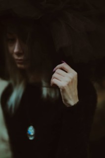 Close-up image with a woman's face partially obscured by tulle fabric, creating an enigmatic feel