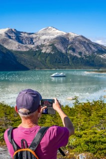 Man photographing the cruise ship Stella Australis in Pia Bay in front of the Pia Glacier, Alberto