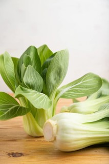 Fresh green bok choy or pac choi chinese cabbage on a brown wooden background. Side view, close up,