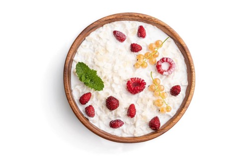 Rice flakes porridge with milk and strawberry in wooden bowl isolated on white background. Top