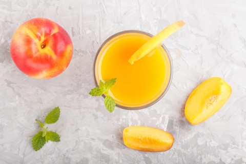 Glass of peach juice on a gray concrete background. Morninig, spring, healthy drink concept. Top