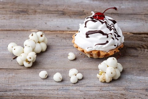 A cake with cream and white berries on a rustic wooden background