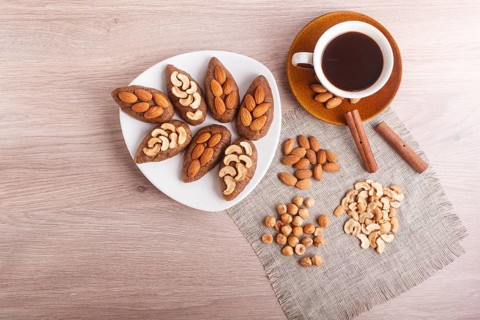 Small cakes potatoes with almonds and cashew nuts on a dessert plate. A cup of coffee, cinnamon,