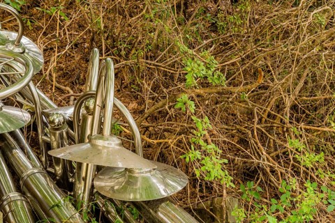 Discarded chrome plated lampposts laying on in dried vegetation on ground in South Korea