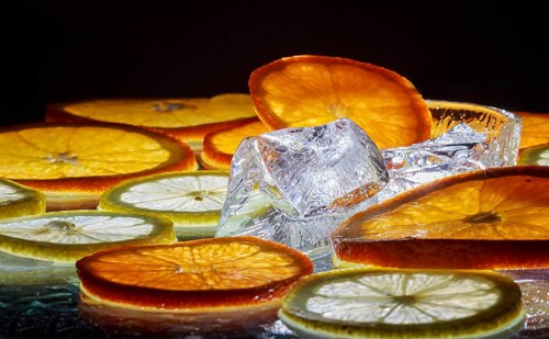 Transparent slices of fresh oranges and lemons on the glass with ice