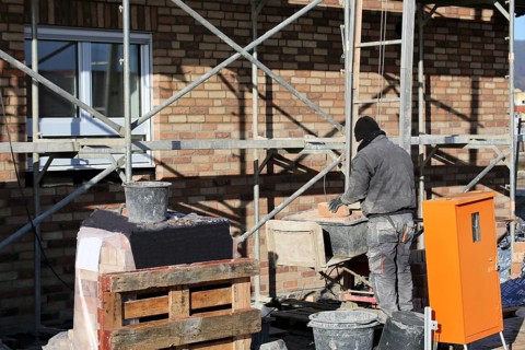 Bricklaying, clinker brick work. Bricklayers clad the facade of a detached house with clinker