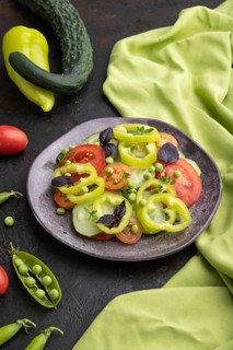 Vegetarian salad from green pea, tomatoes, pepper and basil on a black concrete background and