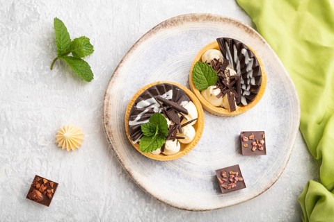 Sweet tartlets with chocolate and cheese cream with cup of coffee on a gray concrete background and