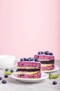 Homemade cake with souffle cream and blueberry jam with cup of coffee and fresh blueberries on gray