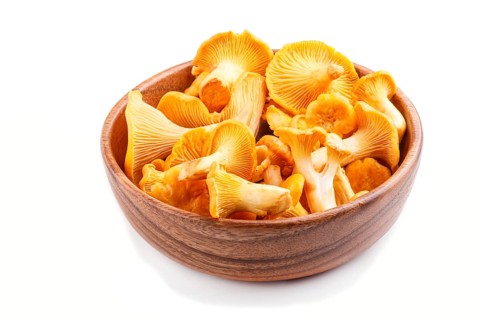 Bunch of chanterelle mushrooms in wooden bowl isolated on white background. side view, close up