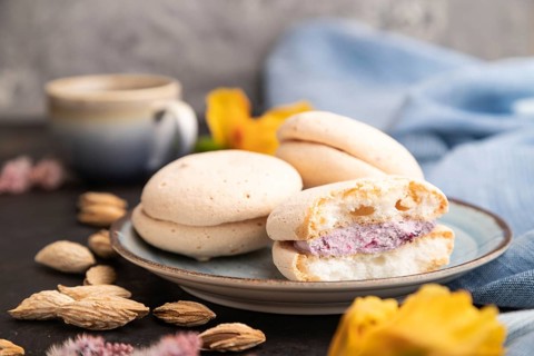 Meringues cakes with cup of coffee on a black concrete background and blue linen textile. Side