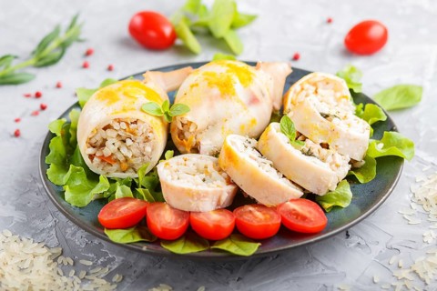 Stuffed baked squid with greens on a blue ceramic plate on a gray concrete background, side view,
