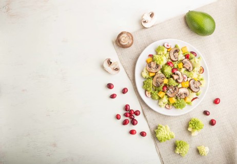 Vegetarian salad from romanesco cabbage, champignons, cranberry, avocado and pumpkin on a white