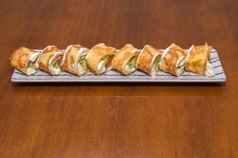 A plate of sushi rolls topped with cream sauce and slices of green lettuce, Majorca, Balearic