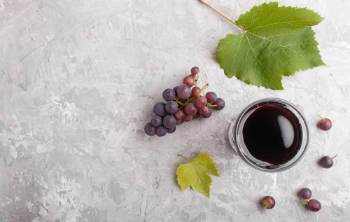 Glass of red grape juice on a gray concrete background. Morninig, spring, healthy drink concept.