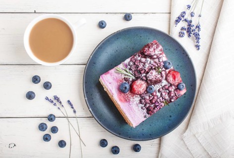 Berry cake with milk cream and blueberry jam on blue ceramic plate with cup of coffee and fresh