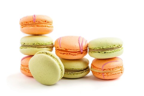 Orange and green macarons or macaroons cakes isolated on white background. side view, close up,