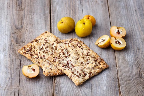 Biscuits with flax, sesame and sunflower seeds and yellow quince fruit on a rustic wooden
