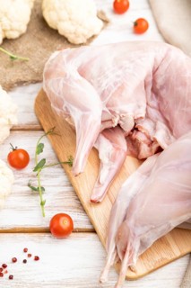 Whole raw rabbit with cauliflower, tomatoes and spices on a white wooden background and linen