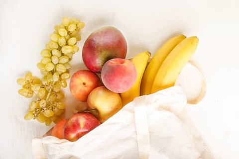 Fruits in reusable cotton textile white bag. Zero waste shopping, storage and recycling concept,