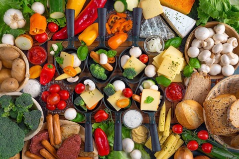 Filled raclette pans with a rich selection of cheese, vegetables and vegetarian meat substitutes,