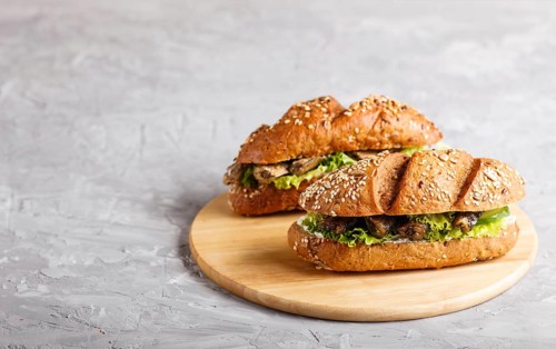 Sprats sandwiches with lettuce and cream cheese on wooden board on a gray concrete background. side