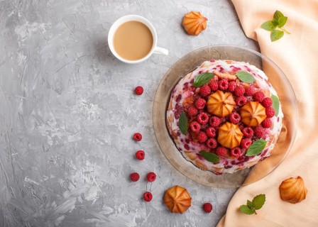 Homemade jelly cake with milk, cookies and raspberry on a gray concrete background with cup of