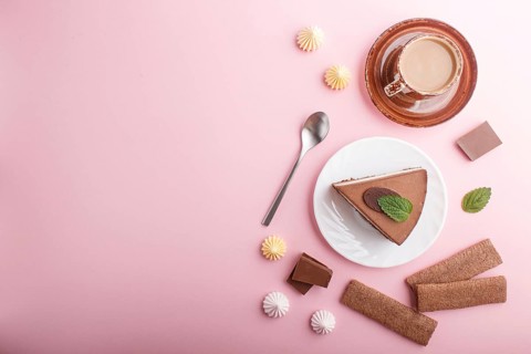 Cake with souffle milk chocolate cream with cup of coffee, meringues on a pink pastel background.