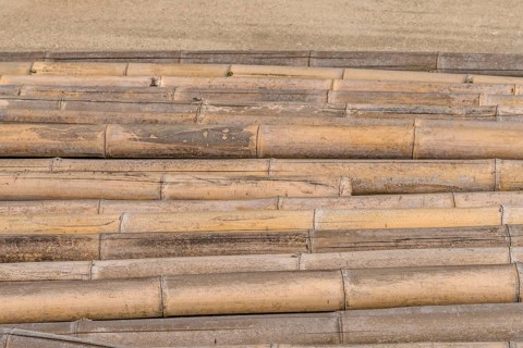 Closeup of weathered cracked bamboo poles laying on concrete in South Korea