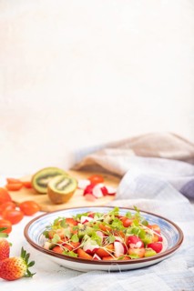 Vegetarian fruits and vegetables salad of strawberry, kiwi, tomatoes, microgreen sprouts on white